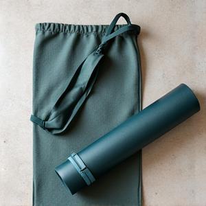Comfortable, adjustable yoga mat carrying strap and a lightweight, durable mat bag, in an outdoor setting.
